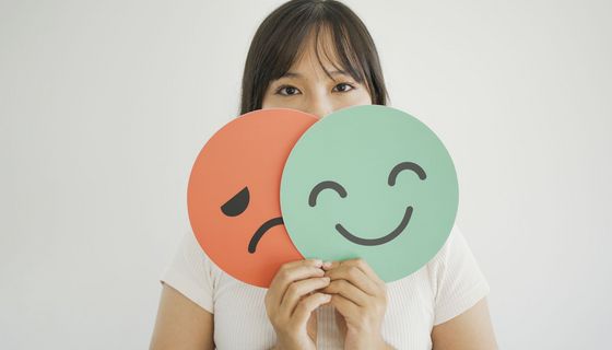 Frau hält Schilder mit lachendem und weinendem Gesicht.