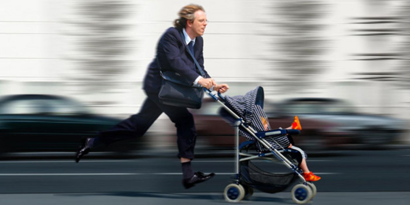 Mann rennt mit Kinderwagen die Straße entlang