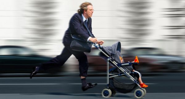 Mann rennt mit Kinderwagen die Straße entlang