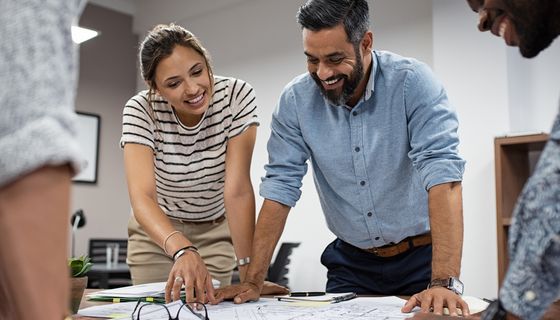 Zwei Büromitarbeiter, gebeugt über einen Plan im Büro.
