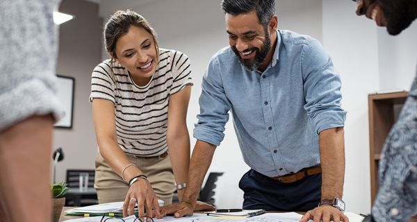 Zwei Büromitarbeiter, gebeugt über einen Plan im Büro.