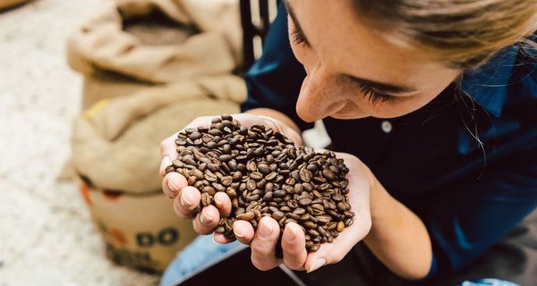 Frau hält Kaffeebohnen in der Hand.