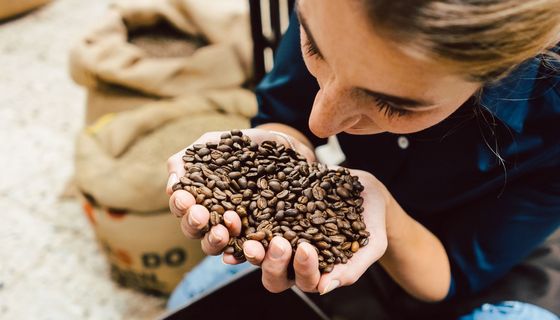 Frau hält Kaffeebohnen in der Hand.