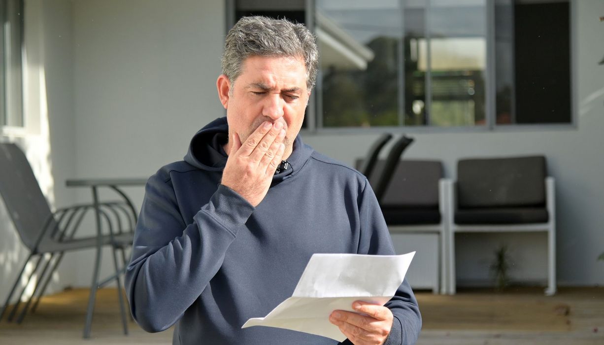 Mann über 50 blickt erschrocken auf ein Schreiben.