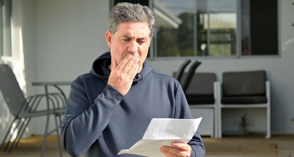 Mann über 50 blickt erschrocken auf ein Schreiben.