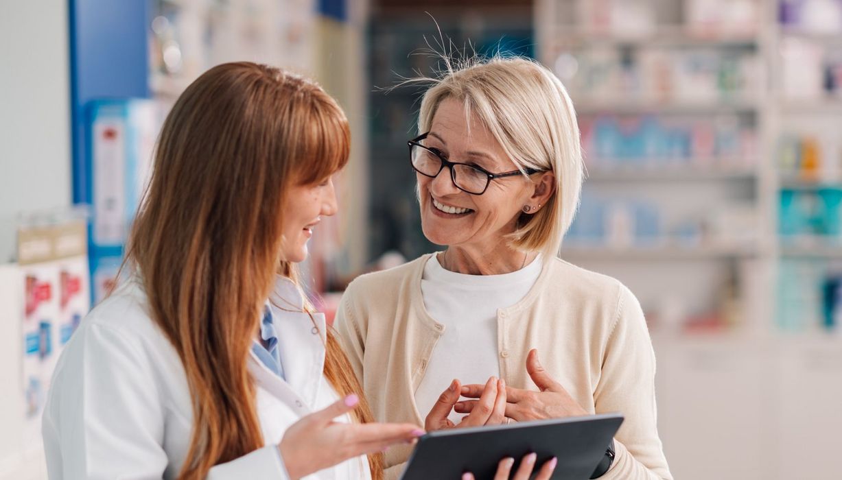 Apothekerin erklärt einer Kundin, etwa 60 Jahre alt, etwas an einem Tablet.