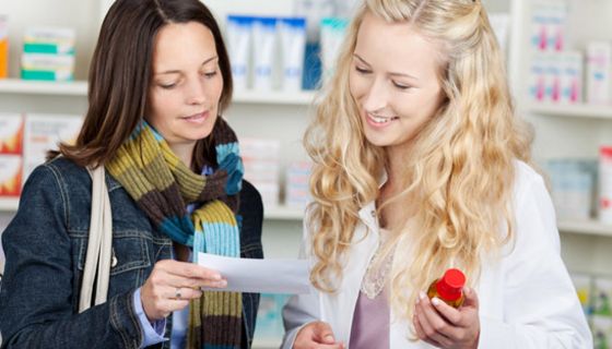 Apothekerin und Kundin betrachten Rezept.