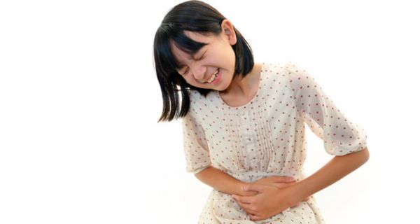 Asiatisches Mädchen, ca. 10 Jahre alt, in geblümtem Kleid, hält sich den schmerzenden Bauch