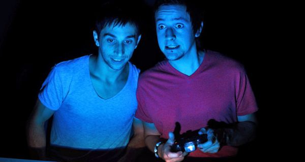 Zwei Jugendliche in einem dunklen Zimmer, spielen auf einer Konsole und haben einen ängstlichen Gesichtsausdruck.