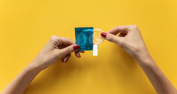 Frau, öffnet eine Kondompackung.