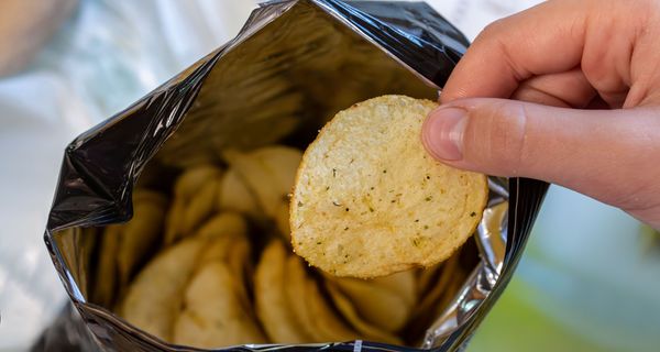 Mann, greift in eine Chipstüte.