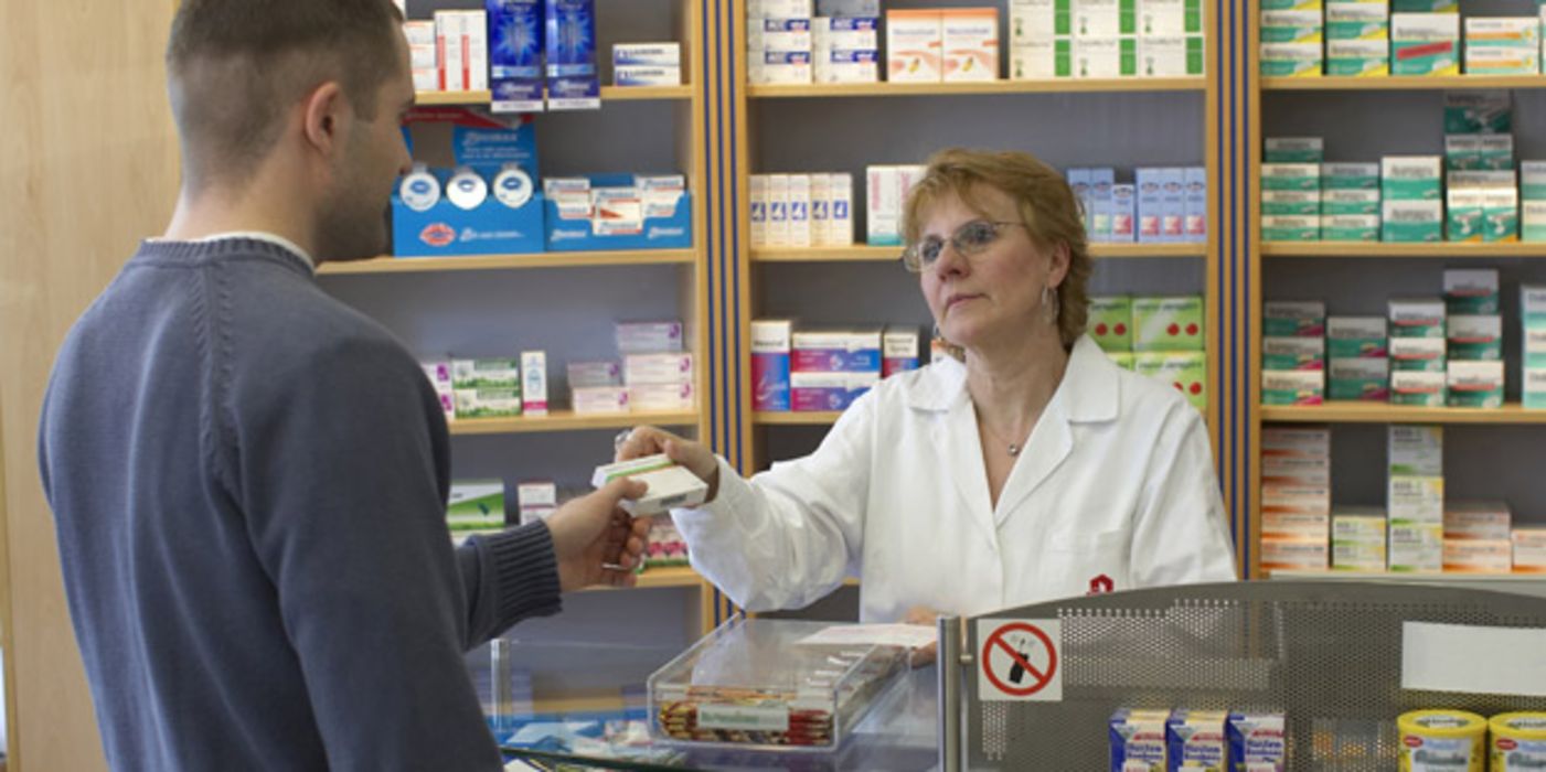 Apothekerin übergibt Arzneimittel an Kunden.