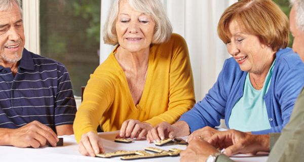 Aktive Senioren sitzen an einem Tisch und spielen ein Gesellschaftsspiel
