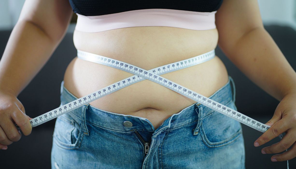 Übergewichtige Frau mit einem Maßband um den Bauch.