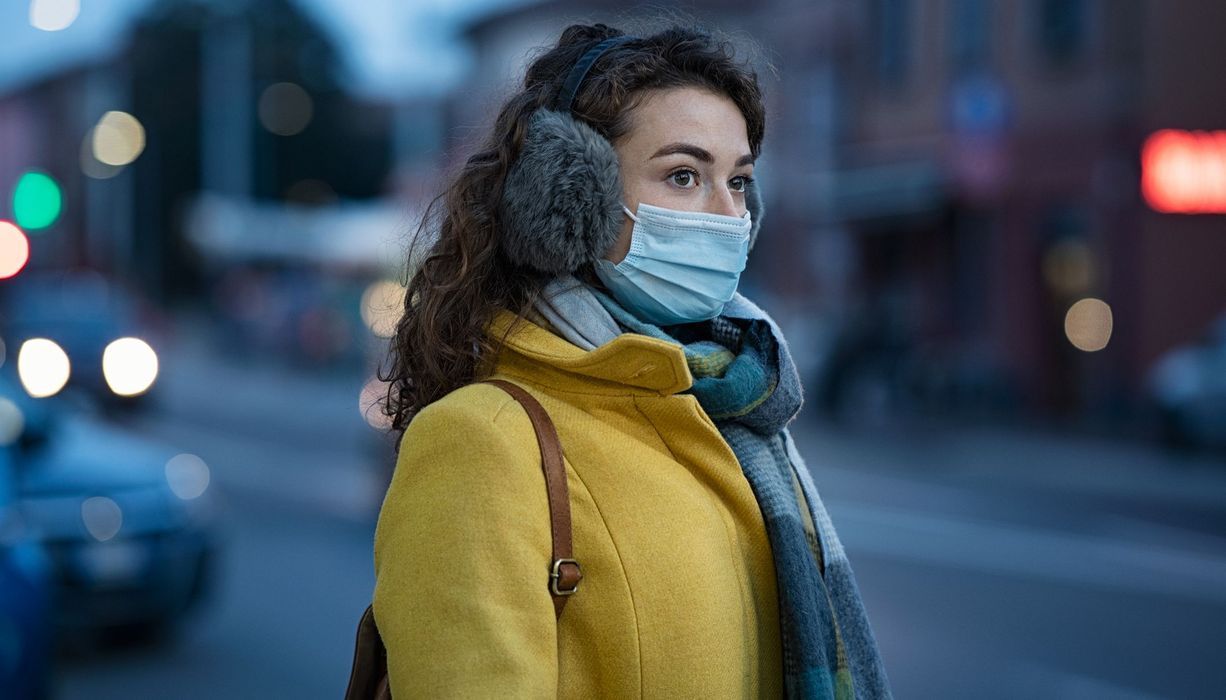 Junge Frau im Winter draußen mit Maske.