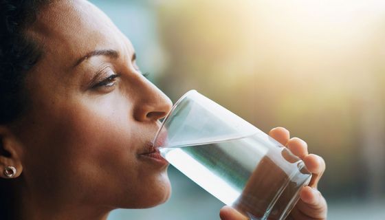 Frau trinkt Wasser aus einem Glas.