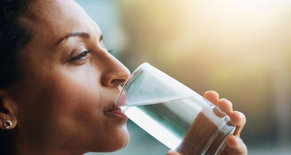 Frau trinkt Wasser aus einem Glas.