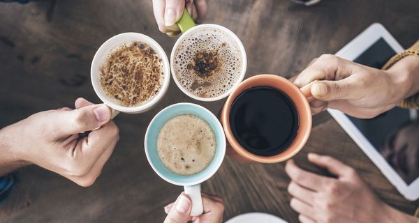 Vier Tassen mit Heißgetränken von oben, darunter Kaffee und Kakao.