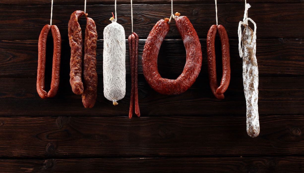Wurst hängt ein einer Leine vor schwarzem Hintergrund.