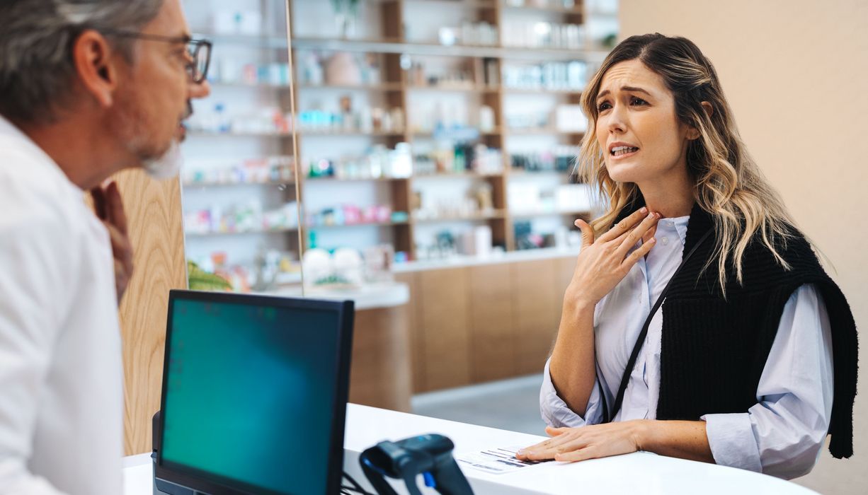 Frau mit Halsschmerzen in der Apotheke.
