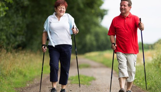 Paar um die 50 beim Nordic-Walking in der Natur im Frühling