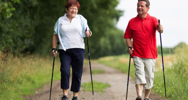 Paar um die 55 beim Nordic Walking auf einem Wanderweg