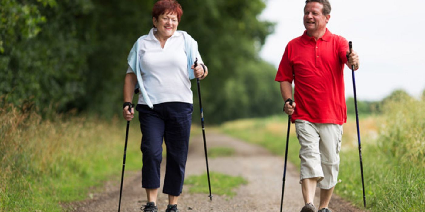 Paar um die 55 beim Nordic Walking auf einem Wanderweg