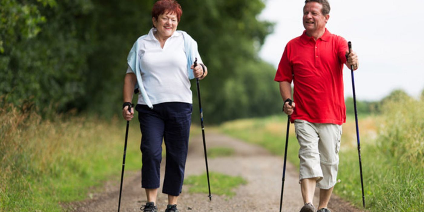 Paar um die 50 beim Nordic-Walking in der Natur im Frühling