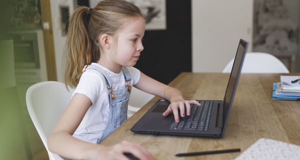 Junges Mädchen, sitzt vor einem Laptop.