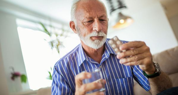 Senior hält eine Packung mit Tabletten in der Hand.