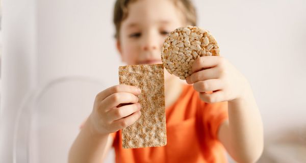 Kleiner Junge mit Knäckebrot und Reiswaffel in der Hand