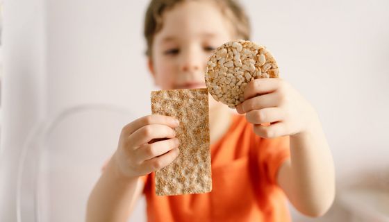 Kleiner Junge mit Knäckebrot und Reiswaffel in der Hand