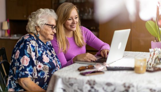 Seniorin und junge Frau, zusammen am Laptop.