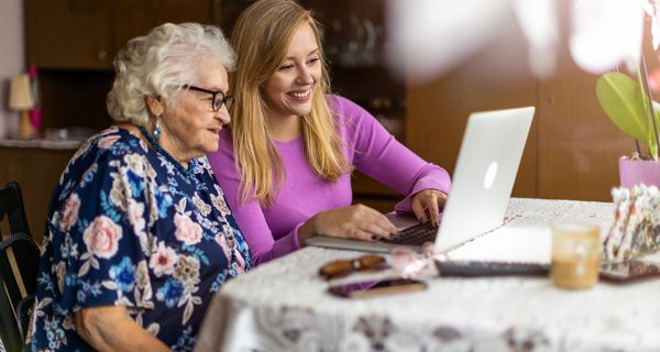 Seniorin und junge Frau, zusammen am Laptop.