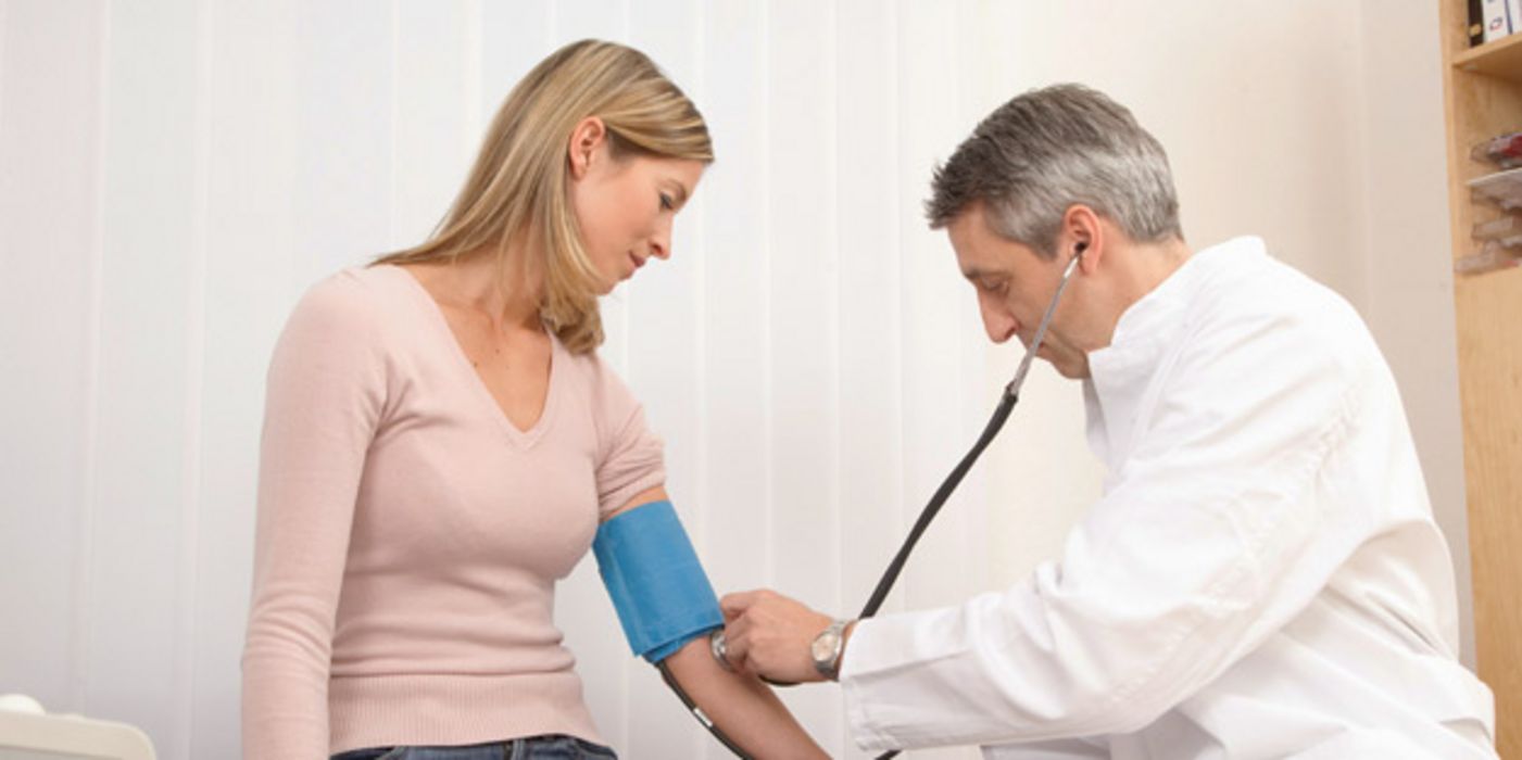 Arzt misst Frau den Blutdruck.