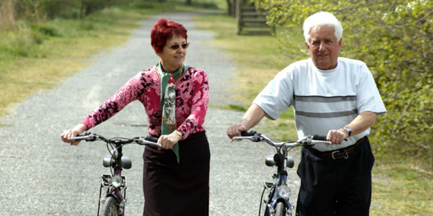 Älteres Paar schiebt Fahrräder.