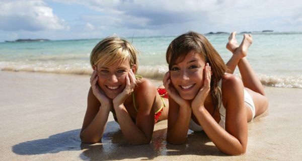 Zwei Frauen liegen am Strand in der Sonne.