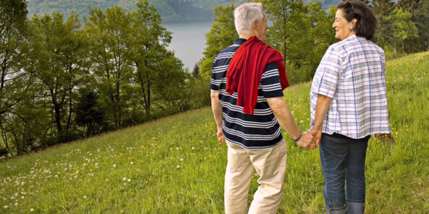 Älteres Paar geht in schöner Landschaft spazieren.