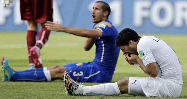 Der Italiener Giorgio Chiellini beklagt sich nachdem Uruguays Spieler Luis Suarez ihn gebissen hat.