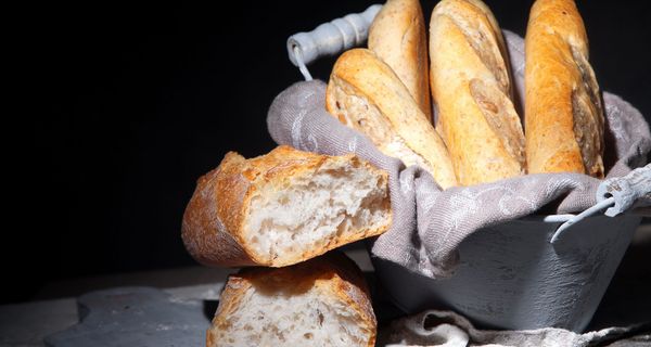 Korb mit Weißbrot vor schwarzem Hintergrund.