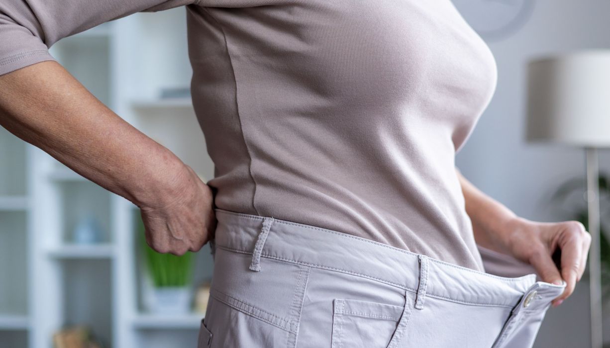 Frau, trägt eine Hose, die ihr zu groß ist.