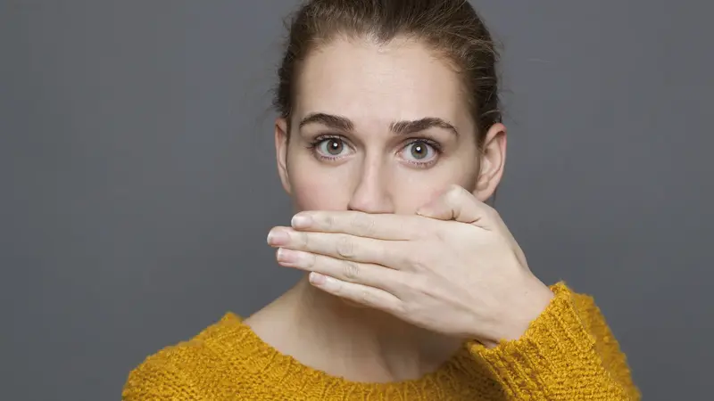 Frau hält sich eine Hand vor den Mund.
