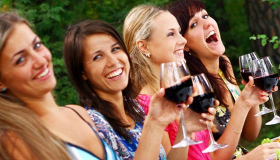 Vier junge Frauen trinken gemeinsam Rotwein.