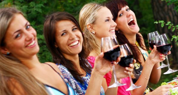 Vier junge Frauen trinken gemeinsam Rotwein.