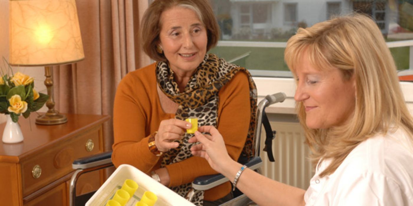 Seniorin bekommt im Altersheim von Altenpflegerin Medikamente verabreicht