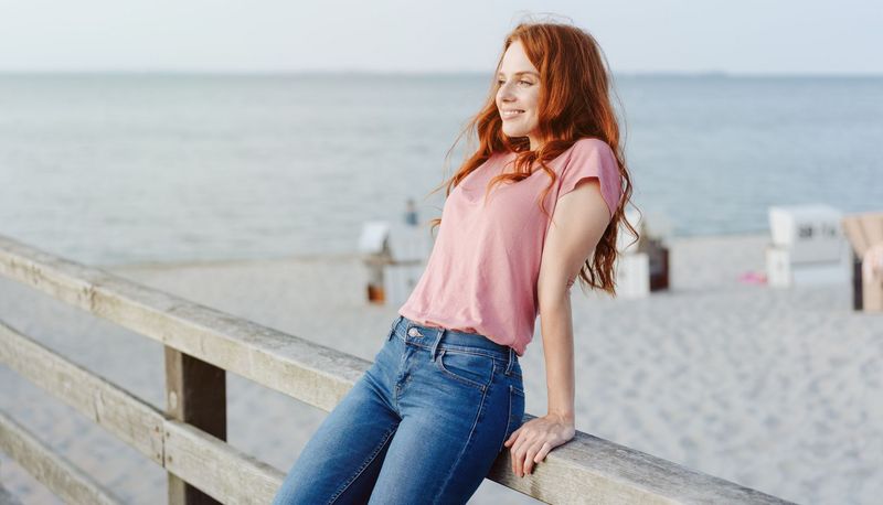 Junge Frau, stützt sich an einem Steg am, Strand im Hintergrund.