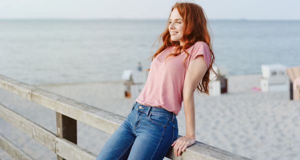 Junge Frau, stützt sich an einem Steg am, Strand im Hintergrund.