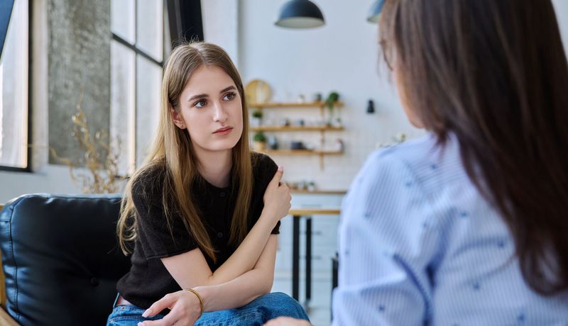 Eine junge Frau spricht mit einer Frau, die ihr gegenüber sitzt.