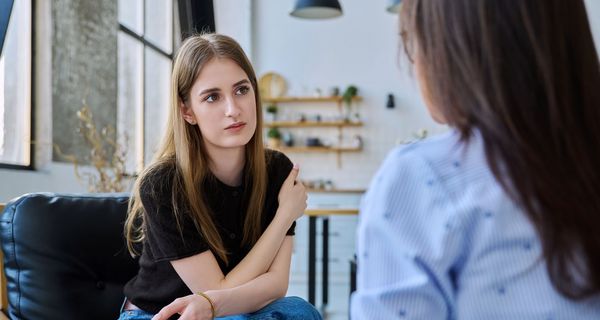 Eine junge Frau spricht mit einer Frau, die ihr gegenüber sitzt.