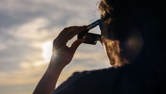 Ein Mann schuat mit einer speziellen Brille für Sonnenfinsternis ins Gegenlicht.